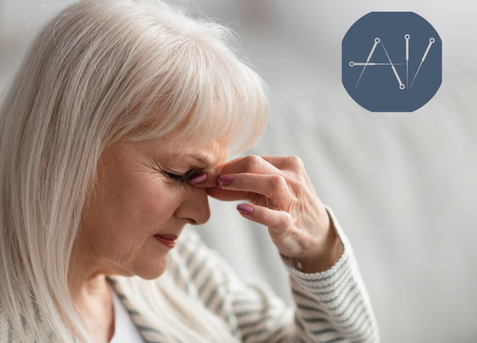 Elderly person with white hair sitting indoors, wearing a striped sweater and resting their hand near their face, soft natural lighting - www.acupunctureandintegrativewellness.com